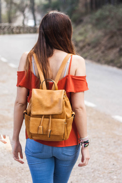 Young woman with light colored leather backpack walking on a mountain hike - Photo, image