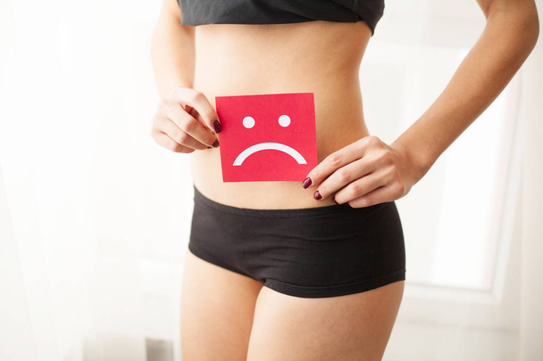 Vaginal or urinary infection and problems concept. Young woman holds paper with sad smile above crotch - Photo, Image