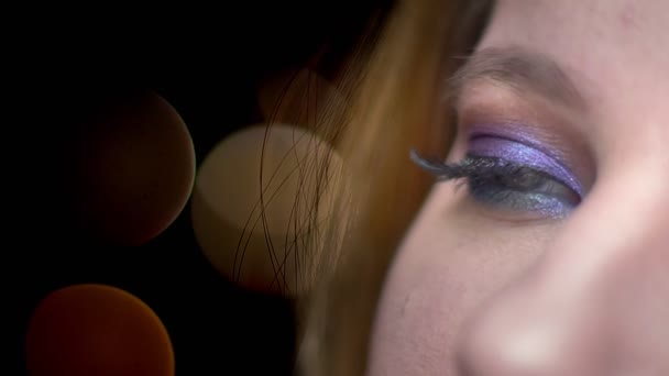 Close-up half-face shoot van jonge mooie vrouwelijke gezicht met de ogen gesloten met vreugdevolle gezichtsuitdrukking met bokeh lichten op de achtergrond - Video