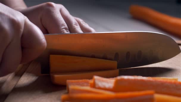 Cutting carrots on a wooden board. counter light. Slow motion - Footage, Video