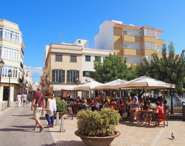Ciutadella, Menorca / Espanja - 1. lokakuuta 2018: ihmiset ympärillä suihkulähde Placa d 'Artruix Ciutadella, vanha pääkaupunki Menorca ympäröivillä kahviloilla - Valokuva, kuva