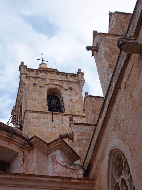 青い曇り空に対してメソルカのラ・シウタデッラのサンタ・マリア大聖堂の鐘塔とガーゴイルのクローズアップビュー - 写真・画像