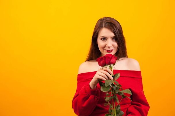 Romantická mladá žena s červenými růžemi na žlutém pozadí - Fotografie, Obrázek