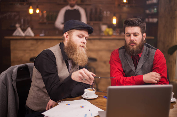 Dos hombres de negocios barbudos teniendo una reunión informal en una cafetería vintage
 - Foto, Imagen
