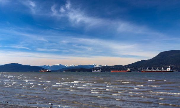 Vancouver harbor, ocean tankers waiting for loading in port white waves in a sunny windy day on the background scenery of snow-capped mountain  - Φωτογραφία, εικόνα