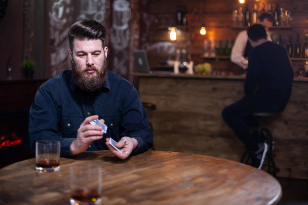schöner bärtiger Mann, der sich neben einem Glas Whiskey in Gedanken verliert - Foto, Bild