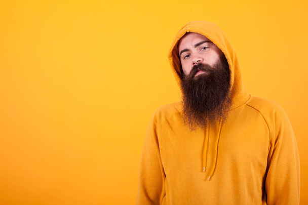 Portrait of Bearded man looking serios at the camera over yellow background - Fotografie, Obrázek
