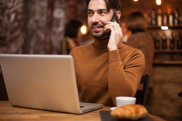 Empresário executivo falando ao telefone enquanto trabalhava em seu laptop em uma cafeteria
 - Foto, Imagem