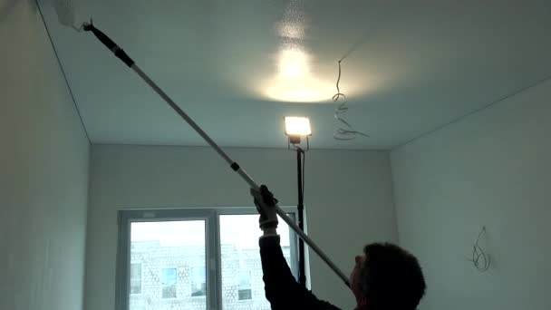 Рабочий рисует потолок роллером. Мужчина рисует белый потолок в комнате
 - Кадры, видео