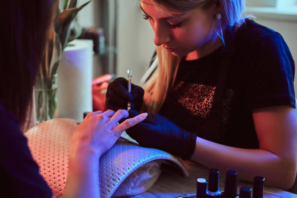 Манікюр спеціаліст робить догляд за нігтями для клієнта в салоні краси. - Фото, зображення