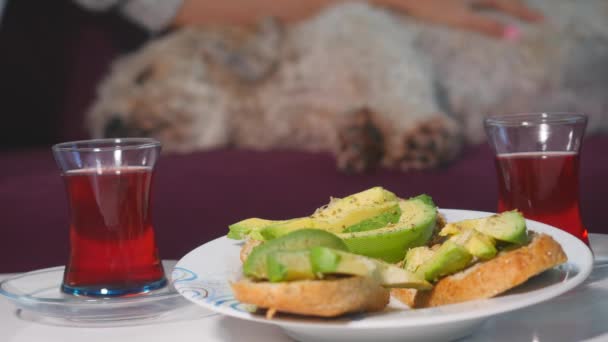 Les femmes prennent leur petit déjeuner avec des sandwichs avocats et du thé rouge. - Séquence, vidéo