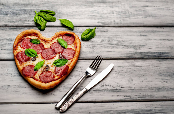 pizza de corazón de queso con salami y hojas de albahaca fresca sobre fondo de madera
 - Foto, Imagen