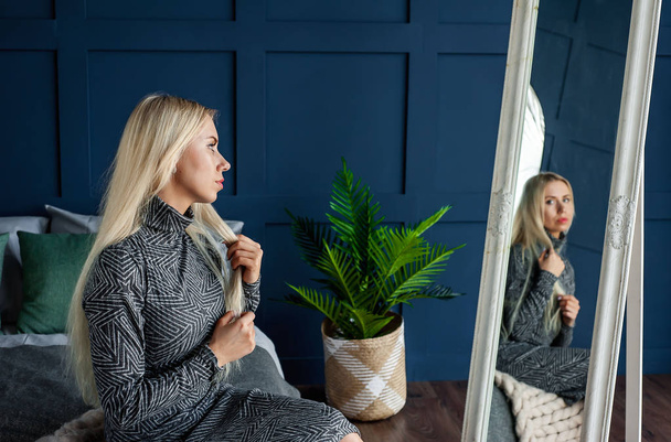 Mladá blondýna žena pózuje ve stylové modré ložnici  - Fotografie, Obrázek