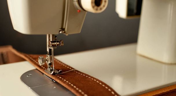 茶色の革ベルトを縫うミシンの近い眺め  - 写真・画像
