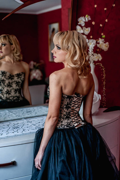 Jeune femme blonde en robe de soirée élégante posant devant le miroir
  - Photo, image
