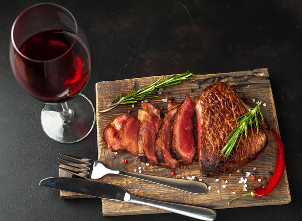 середній рідкісний яловичий стейк на дерев'яній дошці, поданий зі склянкою червоного вина
 - Фото, зображення