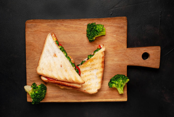 Fresh grilled sandwiches with ham, fresh broccoli and cheese on wooden chopping board - Foto, Imagen