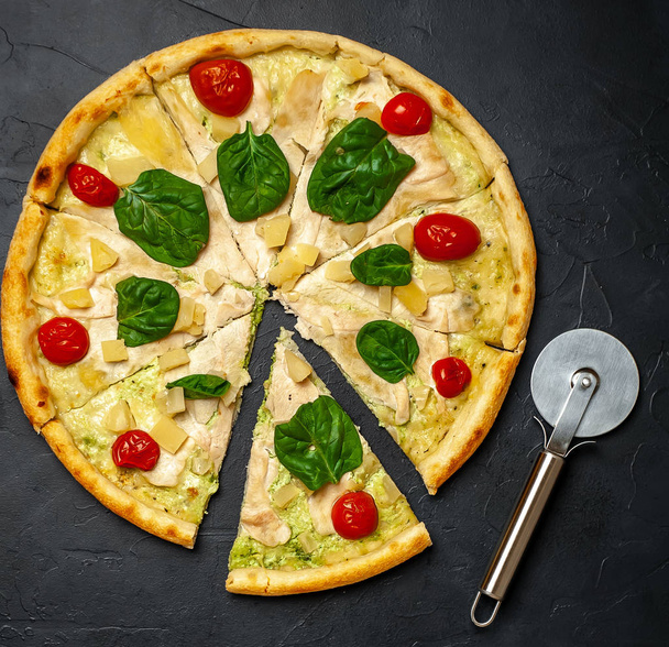 koktélparadicsomos pizza és friss spenót levelei fekete kő háttérben - Fotó, kép