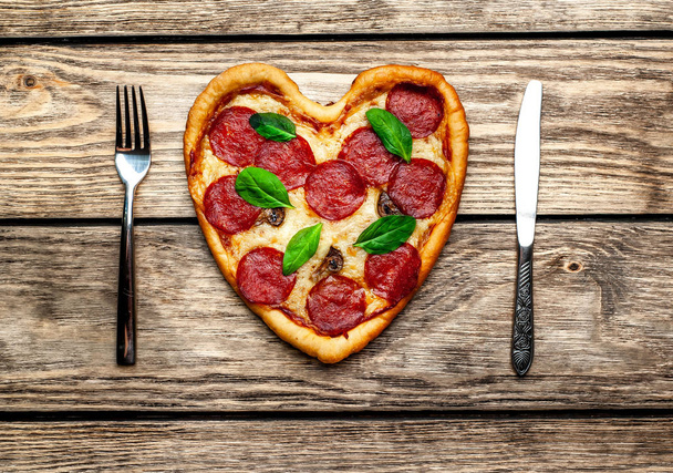 cheese heart pizza with salami and fresh basil leaves on wooden background - Photo, Image