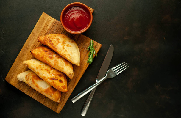 Traditional Latin American fried empanadas with tomato sauce on wooden chopping board  - Photo, Image