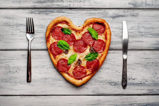 ahşap arka plan üzerinde salam ve taze fesleğen yaprakları ile peynir kalp pizza - Fotoğraf, Görsel