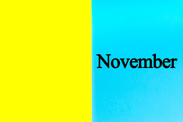 November geschriebene Worte auf blauem und gelbem Hintergrund. Kalender, Monat, Datum und Kopierraumkonzept - Foto, Bild