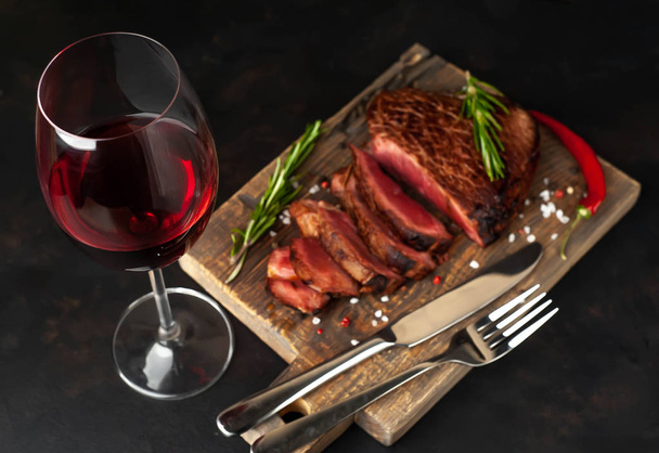 bistecca di manzo medio rara su tavola di legno servita con bicchiere di vino rosso
 - Foto, immagini