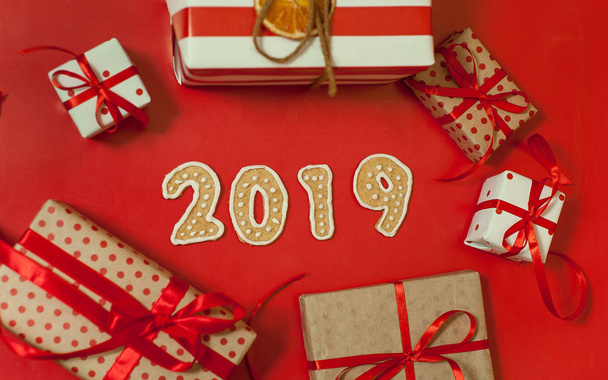 Pile of gift boxes with red bows and 2019 cookies on bright red background  - Photo, image