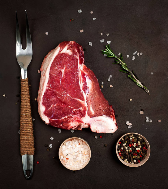 Raw fat steak with spices and rosemary twig on stone background - Photo, Image