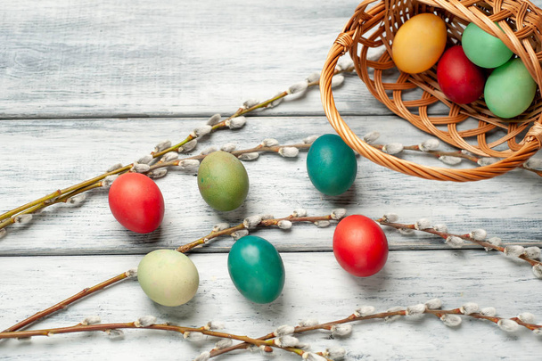 Корзина с красочными пасхальными яйцами и кисками ивы ветви на белом деревянном фоне
 - Фото, изображение
