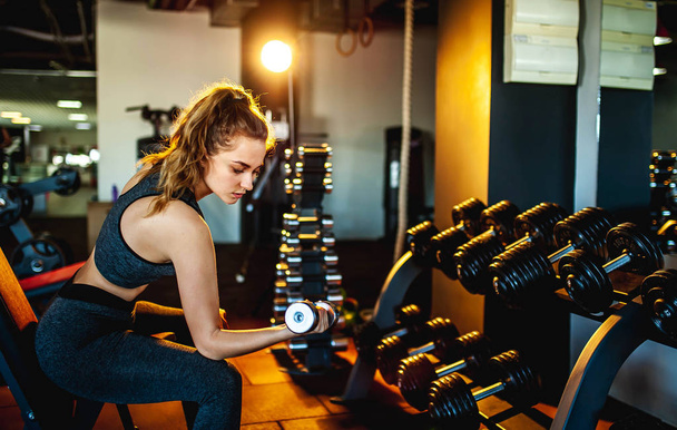 Jeune femme sportive faisant de l'exercice avec haltère dans la salle de gym
 - Photo, image