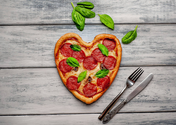 kaas hart pizza met salami en verse basilicum blaadjes op houten achtergrond - Foto, afbeelding