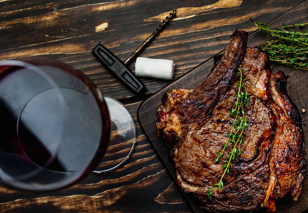 Top view of steak with rosemary twigs served with glass of red wine on wooden table  - Fotoğraf, Görsel