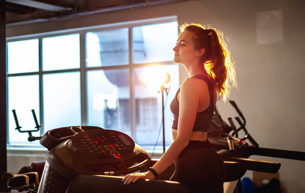 Jeune femme sportive entraînement muscles à la salle de gym vide
   - Photo, image