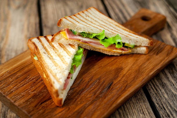 Свіжі домашні бутерброди на грилі на дерев'яній дошці
 - Фото, зображення