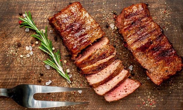 steaks de porc grillés aux épices et romarin sur planche à découper en bois
  - Photo, image