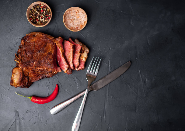 Vette gegrilde varkensvlees Steak met specerijen en Chili peper op zwarte stenen achtergrond - Foto, afbeelding