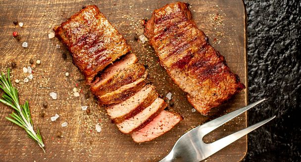steaks de porc grillés aux épices et romarin sur planche à découper en bois
  - Photo, image