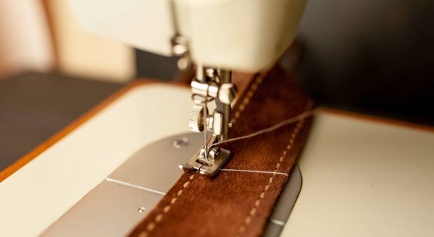 Close view of sewing machine sewing brown leather belt  - Photo, Image