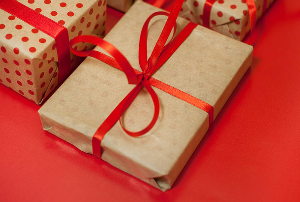 Σωρός από κουτιά δώρων με κόκκινους φιόγκους σε φωτεινό κόκκινο φόντο  - Φωτογραφία, εικόνα