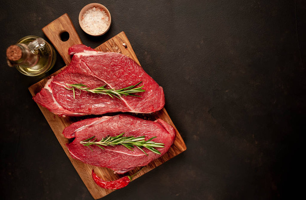 Steaks de bœuf cru aux épices et romarin sur fond de pierre
 - Photo, image
