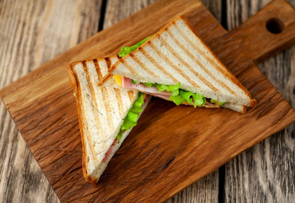 Sandwiches a la parrilla caseros frescos en tablero de madera
 - Foto, imagen