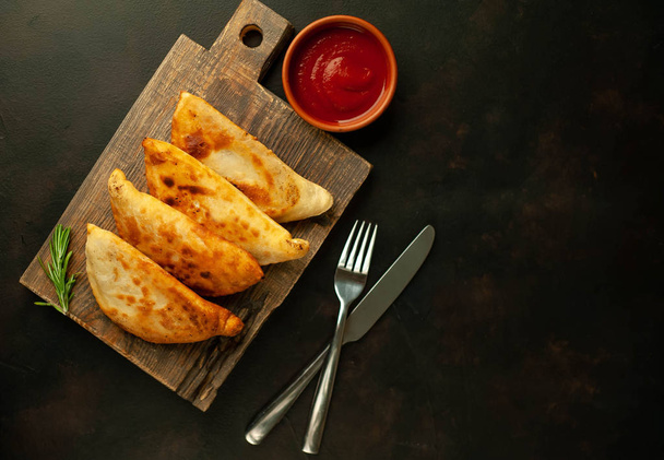Traditional Latin American fried empanadas with tomato sauce on wooden chopping board  - Photo, Image