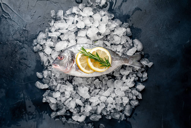 Vue rapprochée du poisson frais avec tranches de citron et romarin sur pile de glace froide concassée
 - Photo, image