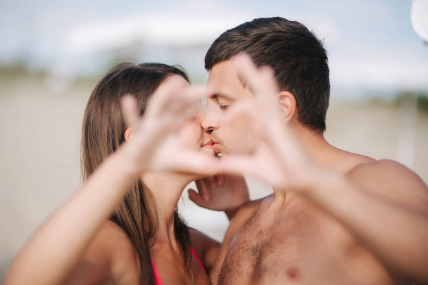 Szczęśliwa Młoda para całować i zrobić serce przez ręce. Para spacery na plaży. Miłość - Zdjęcie, obraz