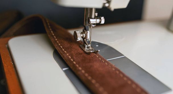 Близкий вид швейной машинки с коричневым кожаным ремнем
  - Фото, изображение