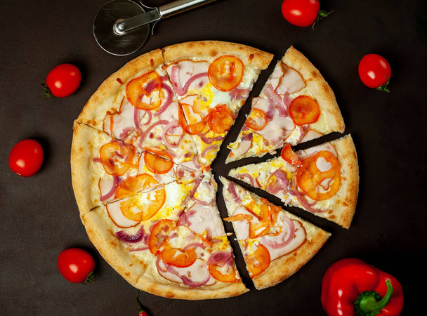 Verse groente pizza met ham op zwarte stenen achtergrond - Foto, afbeelding