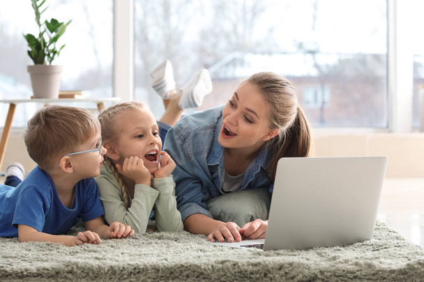 Madre joven con niños pequeños viendo dibujos animados en casa
 - Foto, Imagen