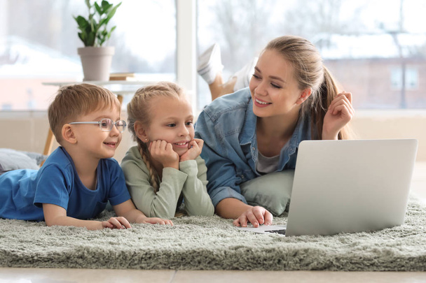 Jonge moeder met kleine kinderen kijken cartoons thuis - Foto, afbeelding