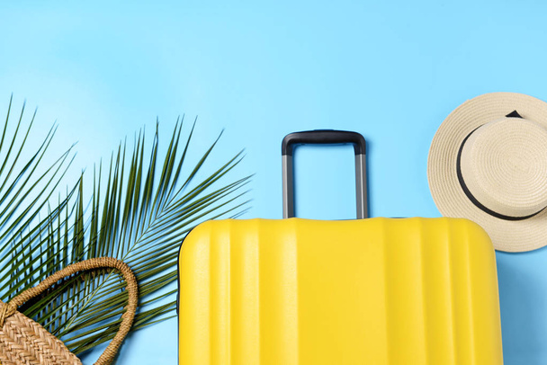 Suitcase, beach bag, palm leaves and hat on color background. Travel concept - Photo, Image